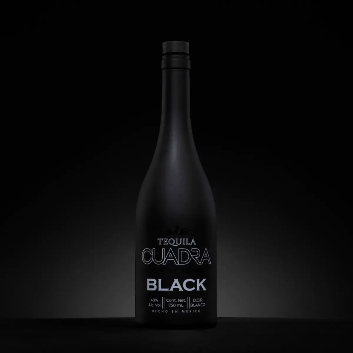 Bouteille de tequila Cuadra Black inspirée du design emblématique Agape, entièrement revêtue d’un noir mat. Son esthétique monochrome haut de gamme fait écho à la tequila noire qu’elle contient, tandis qu’une sérigraphie phosphorescente discrète révèle des effets lumineux sous UV, créant une expérience de marque immersive pour les bars et clubs.