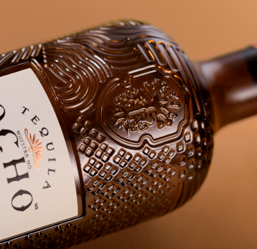 Gros plan haute définition sur la bouteille en verre du téquila premium Los Alambiques Tequila Ocho Extra Añejo (Casa Cuervo), présentant une texture de verre complexe et une gravure personnalisée pour une identité mexicaine authentique.