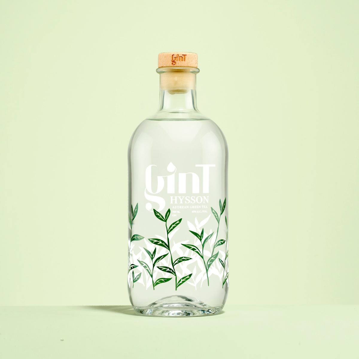 Bouteille de spiritueux au corps cylindrique et épaulement arrondi 70cl. Design moderne pour spiritueux. Bague Plate, Verre Extra-blanc. Sérigraphie d'un logo et de motifs végétaux verts.