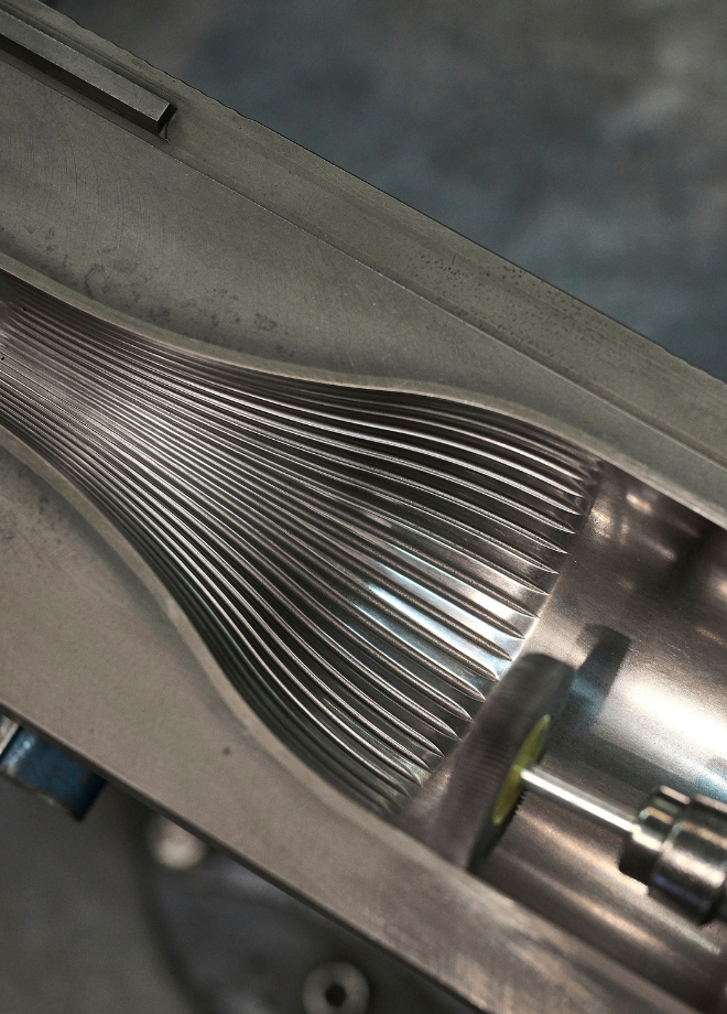 Flacon MDDS à corps cannelé vertical destiné aux vins. Le moule industriel en métal révèle un fût texturé strié, promesse d'une bouteille au design unique et raffiné.