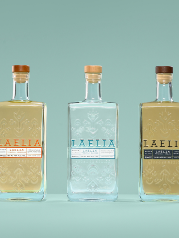 LAELIA TEQUILA. Flacon de spiritueux de 70cl, forme carrée/rectangulaire, corps droit, épaules marquées, base épaisse, en verre Extra-Blanc, avec bague plate. La bouteille centrale présente une sérigraphie blanche. Les bouteilles latérales comportent une sérigraphie blanche et un laquage corps plein, doré pour l'une et bronze pour l'autre.